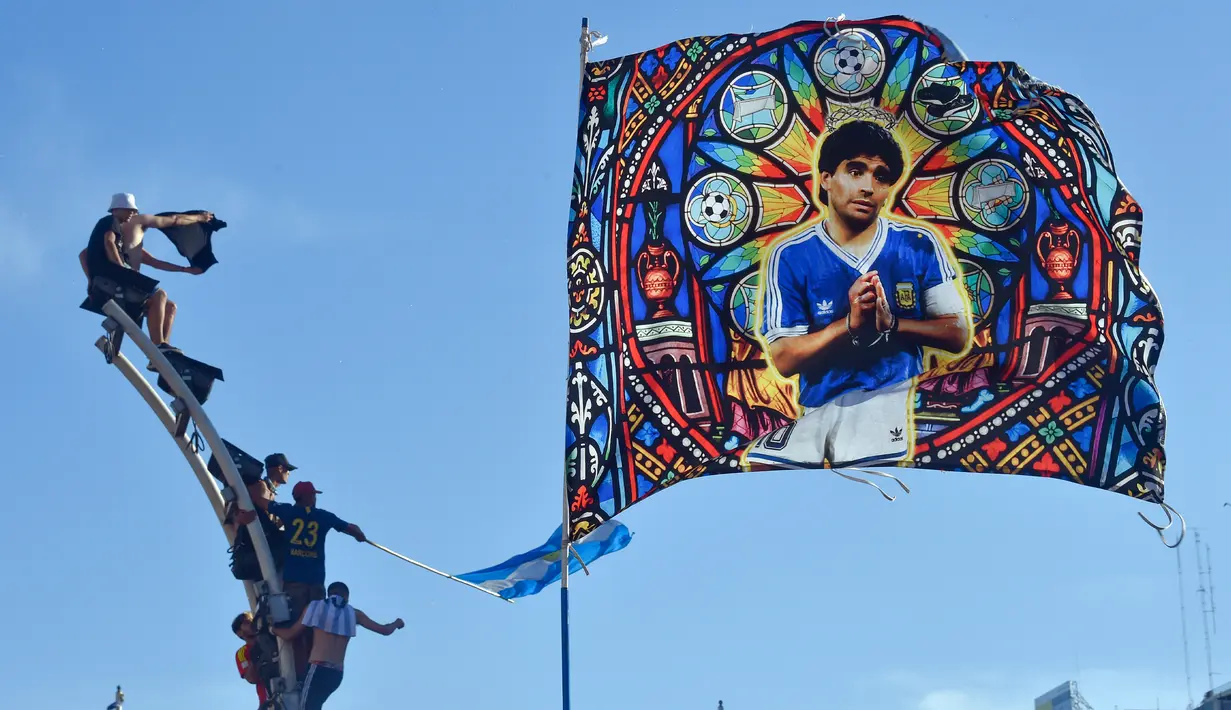 Bendera mendiang legenda sepak bola Diego Maradona melambai di atas para suporter yang merayakan kemenangan Argentina atas Prancis pada pertandingan sepak bola final Piala Dunia Qatar 2022 di Buenos Aires, Argentina, 18 Desember 2022. Argentina menang 4-2 dalam drama adu penalti setelah pertandingan berakhir imbang dengan skor 3-3. (AP Photo/Gustavo Garello)