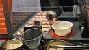 Robot koki bernama Sophie meracik semangkuk laksa saat demonstrasi memasak di Singapura pada 26 Juli 2019. Selain itu robot koki tersebut juga dirancang bisa membersihkan meja dapurnya secara otomatis. (Roslan RAHMAN / AFP)