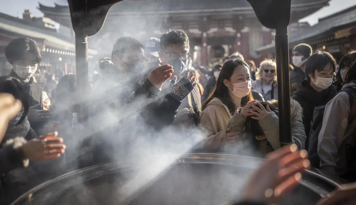 Orang-orang berdoa di sekitar pembakar dupa di kuil Sensoji menjelang liburan Tahun Baru di Tokyo pada 30 Desember 2022. Kuil Sensoji dikenal sebagai tempat wisata paling terkenal di Tokyo. (AFP/Yuichi Yamazaki)