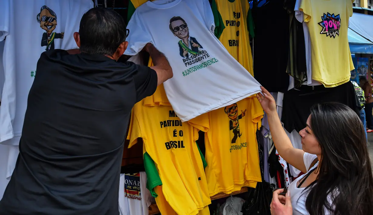 Pembeli memilih kaus bergambar Calon Presiden Brasil, Jair Bolsonaro dari sayap kanan dijajakan di sebuah toko pinggir jalan yang populer di Sao Paulo, 8 Oktober 2018. September lalu, Bolsonaro dirawat setelah ditusuk ketika kampanye. (AFP/NELSON ALMEIDA)