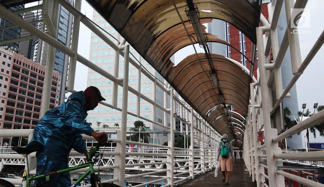 Warga melintasi Jembatan Penyeberangan Orang (JPO) di kawasan Dukuh Atas, Jakarta, Rabu (12/12). Atap JPO Dukuh Atas mengalami kerusakan. (Liputan6.com/JohanTallo)