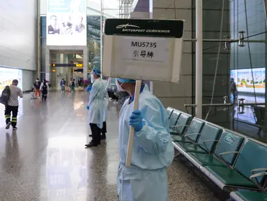 Petugas mengangkat papan untuk memandu kerabat penumpang pesawat China Eastern Airlines setelah gagal tiba di Bandara Internasional Baiyun, Guangzhou, selatan China, Senin (21/3/2022). Pesawat Boeing 737 milik China Eastern Airlines jatuh di Daerah Otonomi Guangxi pada Senin sore. (STR/AFP)