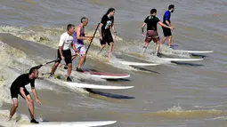 Sejumlah warga saat menikmati bermain surfing di Sungai Dordogne, Saint-Pardon, Prancis (24/7). Fenomena pasang surut besar ini terjadi beberapa kali dalam setahun. (AFP Photo/Georges Gobet)