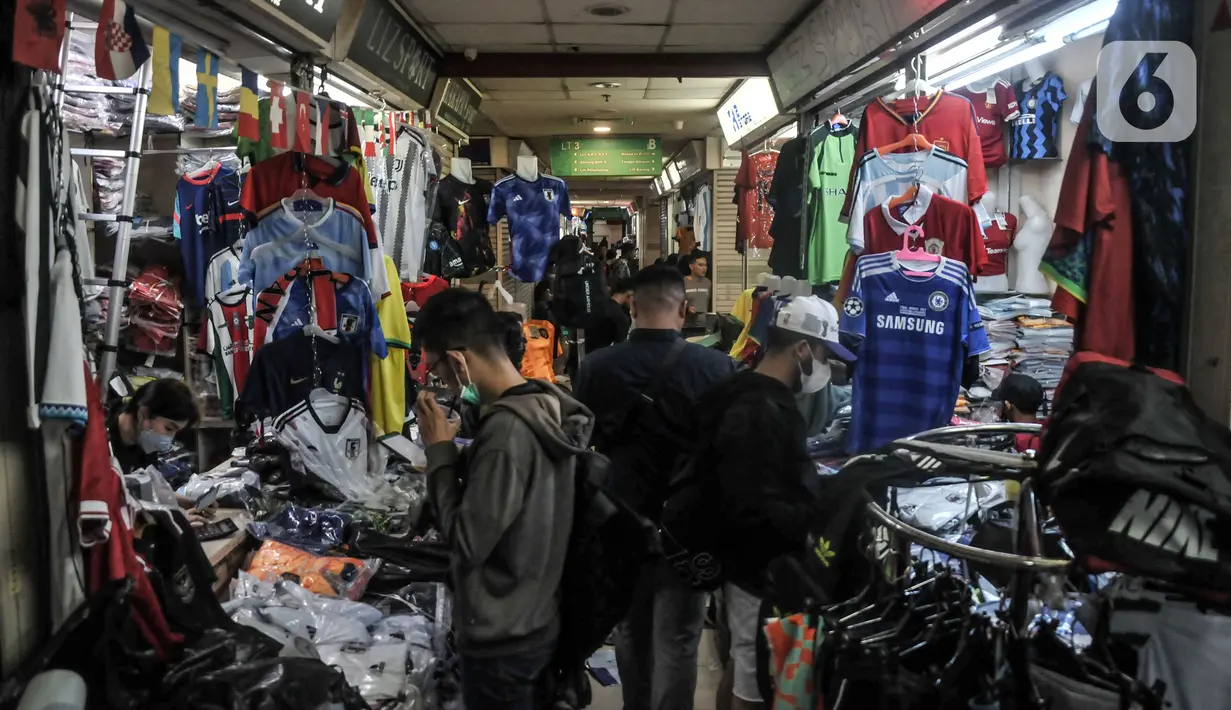Calon pembeli memilih jersey sepak bola yang akan disablon bertema Piala Dunia 2022 di salah satu kios Blok B Pasar Tanah Abang, Jakarta Pusat, Kamis (8/12/2022). Perhelatan Piala Dunia 2022 membawa berkah tersendiri bagi jasa sablon jersey sepak bola di Pasar Tanah Abang yang diakui mengalami peningkatan pesanan hingga 80 persen dibandingkan bulan sebelumnya. (merdeka.com/Iqbal S. Nugroho)