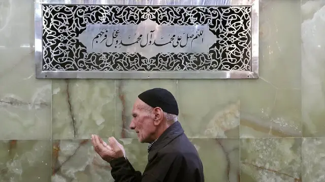 Muslim membaca sholawat di dekat kaligrafi bertuliskan sholawat (Wikimedia Commons)