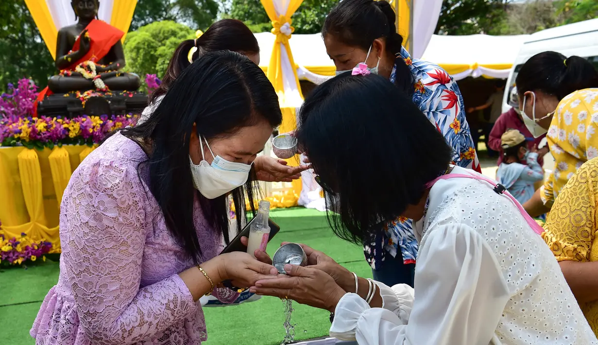 Umat Buddha menuangkan air menurut tradisi, untuk mencegah penyebaran virus corona Covid-19, saat mereka merayakan Tahun Baru Buddha, yang secara lokal dikenal sebagai Songkran, di kuil Prachapirom di Narathiwat (12/4/2022). (AFP/Madaree Tohlala)