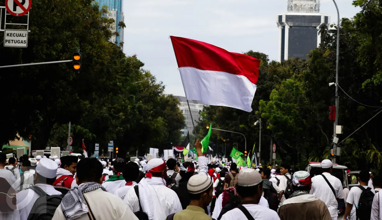Bendera merah putih dikibarkan di antara massa demo 2 Desember yang berjalan kaki menuju Monumen Nasional (Monas), Jakarta Pusat, Jumat (2/12). Demo 2 Desember digelar sebagai lanjutan dari aksi 4 November 2016.  (Liputan6.com/Faizal Fanani)