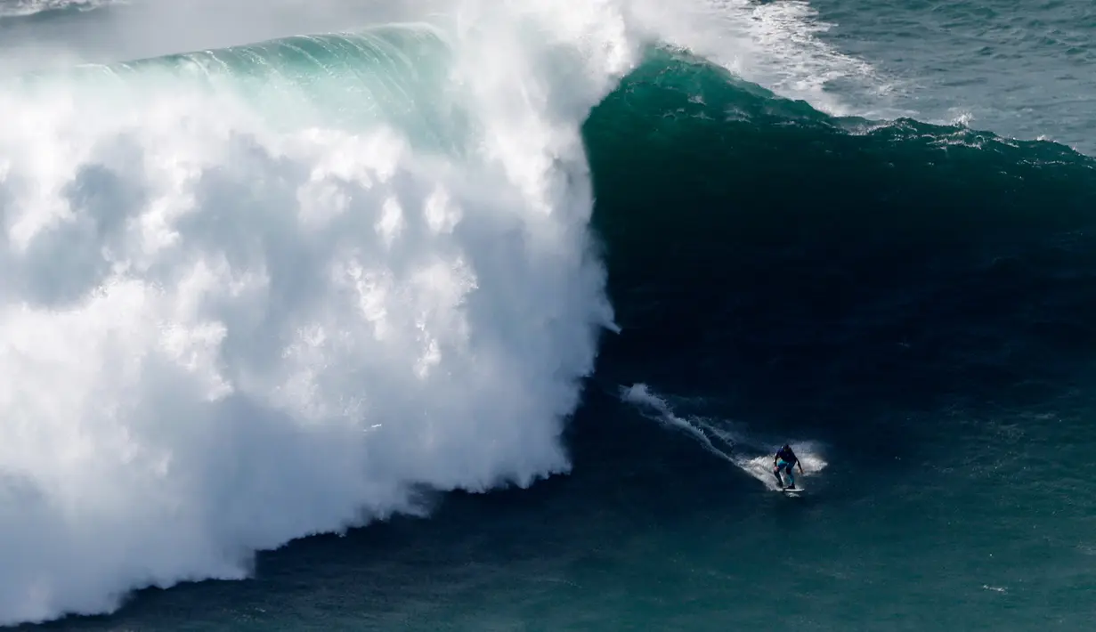 Peselancar unjuk kebolehan saat menaklukkan ombak besar di Praia do Norte atau Pantai Utara, Nazare, Portugal, Rabu (20/11/2019). Ombak di perairan ini disebut-sebut paling menantang dan paling berbahaya di dunia. (AP Photo/Armando Franca)