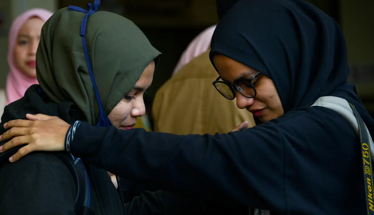 Seorang mahasiswa (kiri) yang dipulangkan dari karantina virus corona atau COVID-19 di Natuna memeluk keluarganya saat tiba di Bandara Internasional Sultan Iskandar Muda, Blang Bintang, Aceh, Senin (17/2/2020). Ini merupakan pemulangan mahasiswa Aceh gelombang pertama. (CHAIDEER MAHYUDDIN/AFP)