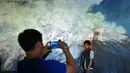 Pengunjung berfoto di salah satu lukisan yang berada di pameran “Pintu Belakang | Derau Jawa" di Galeri Nasional Indonesia, Jakarta (12/3). Pameran ini hasil karya Hanafi yang berasal dari Jawa. (Liputan6.com/Faisal R Syam)