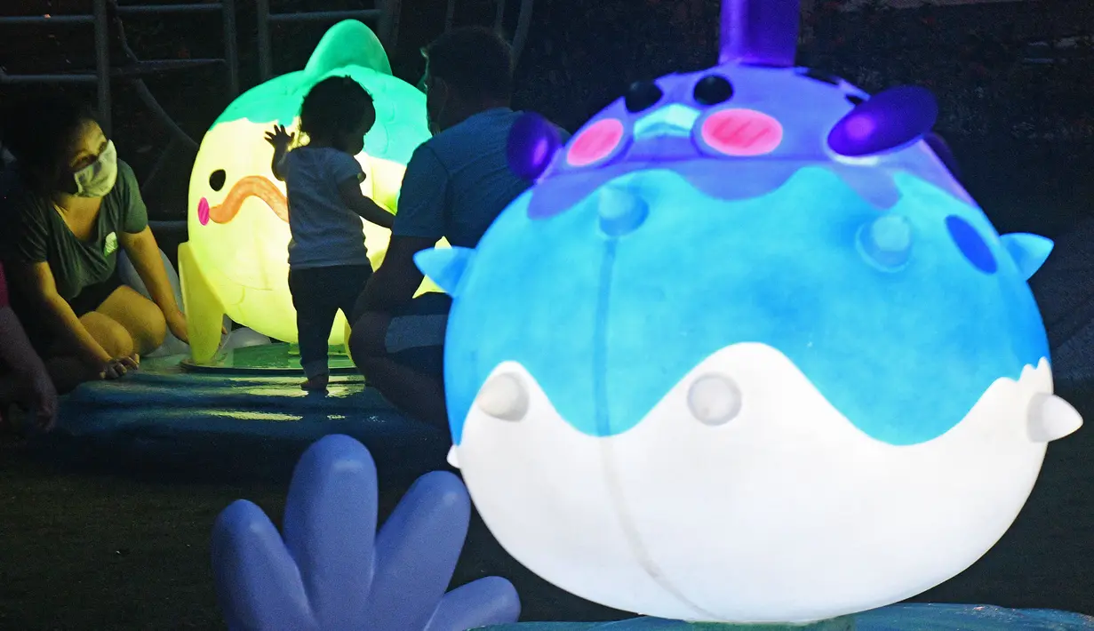 Seorang anak menyentuh instalasi lentera menjelang perayaan Festival Pertengahan Musim Gugur di Singapura (14/9/2020). (Xinhua/Then Chih Wey)
