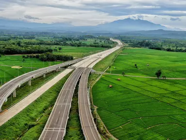 Foto udara pembangunan Gerbang Tol Ujung Jaya Utama bagian dari Tol Cileunyi-Sumedang-Dawuan (Cisumdawu) seksi enam di Kabupaten Majalengka, Jawa Barat, Rabu (28/12/2022). Kementerian Koordinator Bidang Perekonomian melalui KPPIP meninjau progress dan optimalisasi untuk akses jalan tol menuju Bandara Kertajati dan solusi antisipasi kemacetan jalan nasional Bandung ke Majalengka serta target fungsional secara keseluruhan di kwartal satu 2023 dalam mendukung arus mudik lebaran. (Liputan6.com/Angga Yuniar)