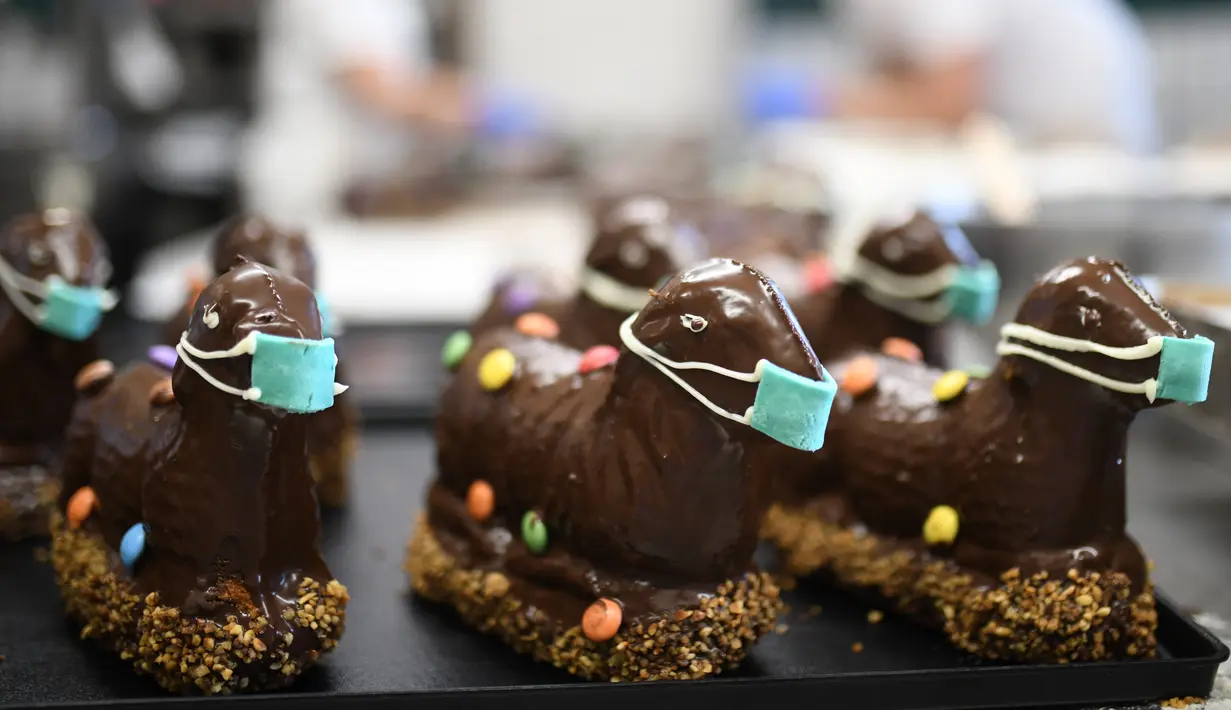 Kue cokelat Paskah berbentuk domba tradisional dengan masker dipajang di toko roti Schuerener Backparadies, Dortmund, Jerman, Rabu (8/4/2020). Pembuatan kue Paskah dengan masker bertepatan dengan pandemi virus corona COVID-19. (Ina FASSBENDER/AFP)