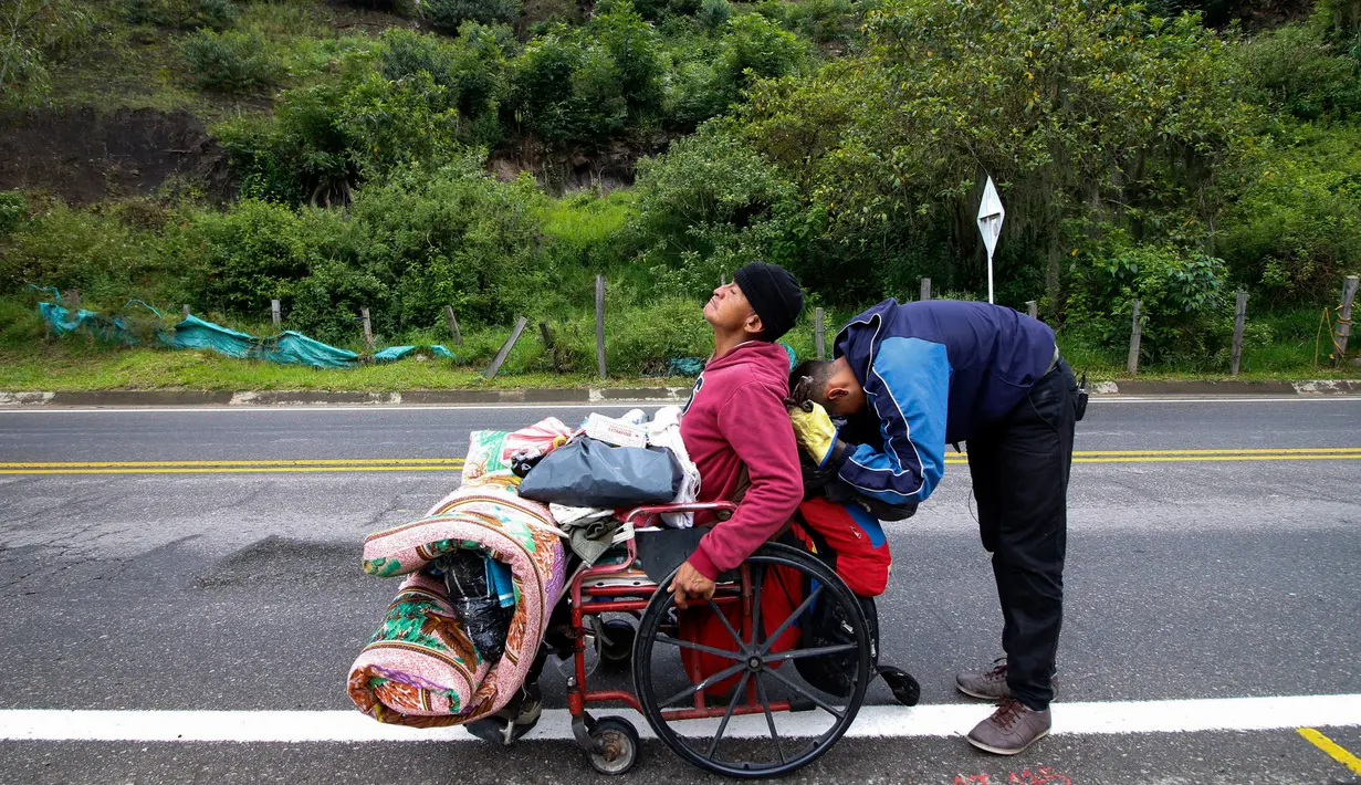 Migran Venezuela, Jefferson Alexis dan ayahnya, Jose Agustin Lopez, duduk di kursi roda, beristirahat ketika melakukan perjalanan yang menghubungkan Cucuta dan Pamplona di Norte de Santander Department, Kolombia, 15 September 2018. (AFP/SCHNEYDER MENDOZA)