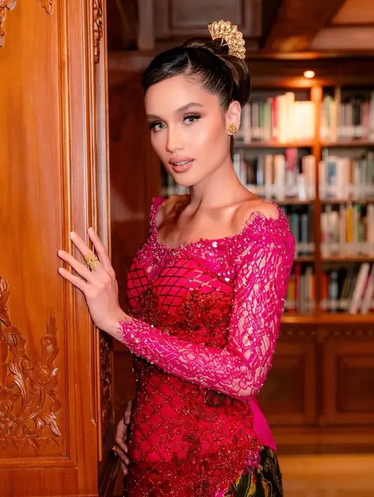 Berpose di tengah nuansa klasik perpustakaan dengan sentuhan kayu ukir yang hangat, Cinta tampil memesona dalam balutan kebaya merah marun dengan aksen brokat transparan di bagian lengan.  [@philipekarunia].