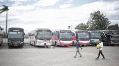 Dua pria melintasi bus yang terparkir di Terminal terpadu tipe A Pondok Cabe di Pamulang, Tangerang Selatan, Senin (31/12). Mulai 31 Desember , terminal yang memiliki luas mencapai 25.995 m2 tersebut resmi beroperasi. (Liputan6.com/Faizal Fanani)