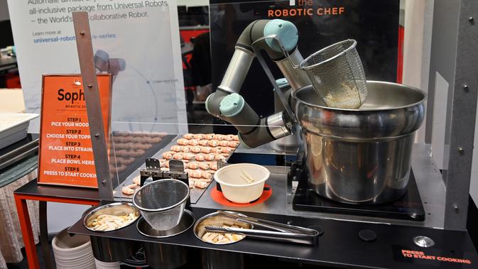 Robot koki bernama Sophie meracik semangkuk laksa saat demonstrasi memasak di Singapura pada 26 Juli 2019. Robot koki ini bisa merebus mie, menambahkan udang, dan menuangkan sup ke sebuah mangkuk. (Roslan RAHMAN / AFP)