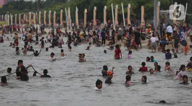 Pengunjung memadati kawasan Pantai Ancol di Taman Impian Jaya Ancol, Jakarta, Rabu (4/5/2022). Objek wisata tersebut kembali ramai dikunjungi wisatawan pada saat liburan Hari Raya Idul Fitri 1443 H setelah dua tahun sebelumnya sempat mengalami penurunan kunjungan wisatawan akibat pandemi Covid-19. (Liputan6.com/Herman Zakharia)