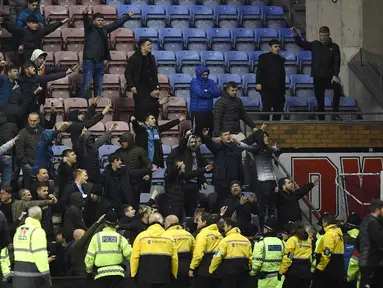 Pendukung Manchester City bereaksi setelah tim kesayangnya dikalahkan Wigan Athletic pada babak kelima Piala FA di Stadion DW, Senin (19/2). Suporter Manchester City melemparkan berbagai benda, termasuk papan iklan, ke arah lapangan. (Oli SCARFF/AFP)