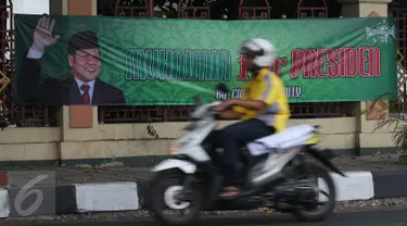 Pengendara motor melintasi spanduk bertuliskan 'Muhaimin for President' di pagar Masjid Sunda Kelapa, Jakarta, Sabtu (12/9). Pemasangan spanduk itu melanggar UU tentang larangan penggunaan tempat ibadah sebagai tempat kampanye. (Liputan6.com/Angga Yuniar)