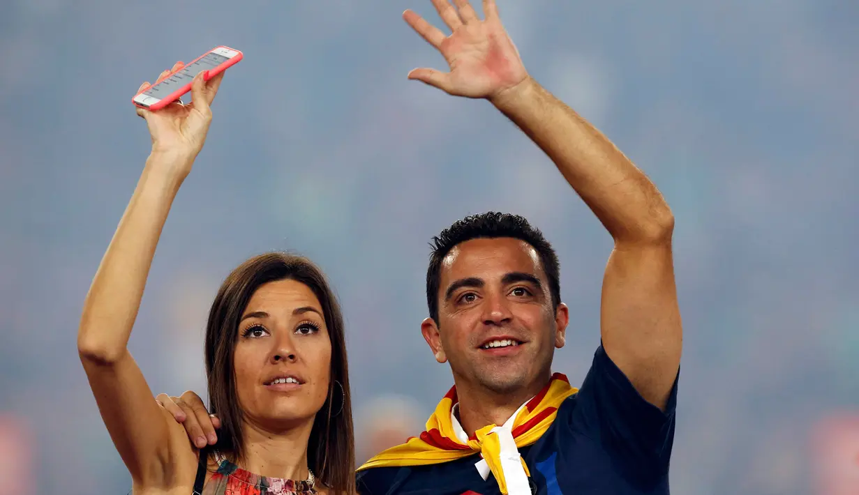 Gelandang Barcelona, Xavi Hernandes bersama istrinya menyapa pengemarnya saat parade di stadion Camp Nou, Spanyol (7/6/2015). ini merupakan musim terakhir Xavi berkostum Barcelona yang akan pindah ke klub papan atas Qatar, Al Sadd. (REUTERS/Albert Gea)