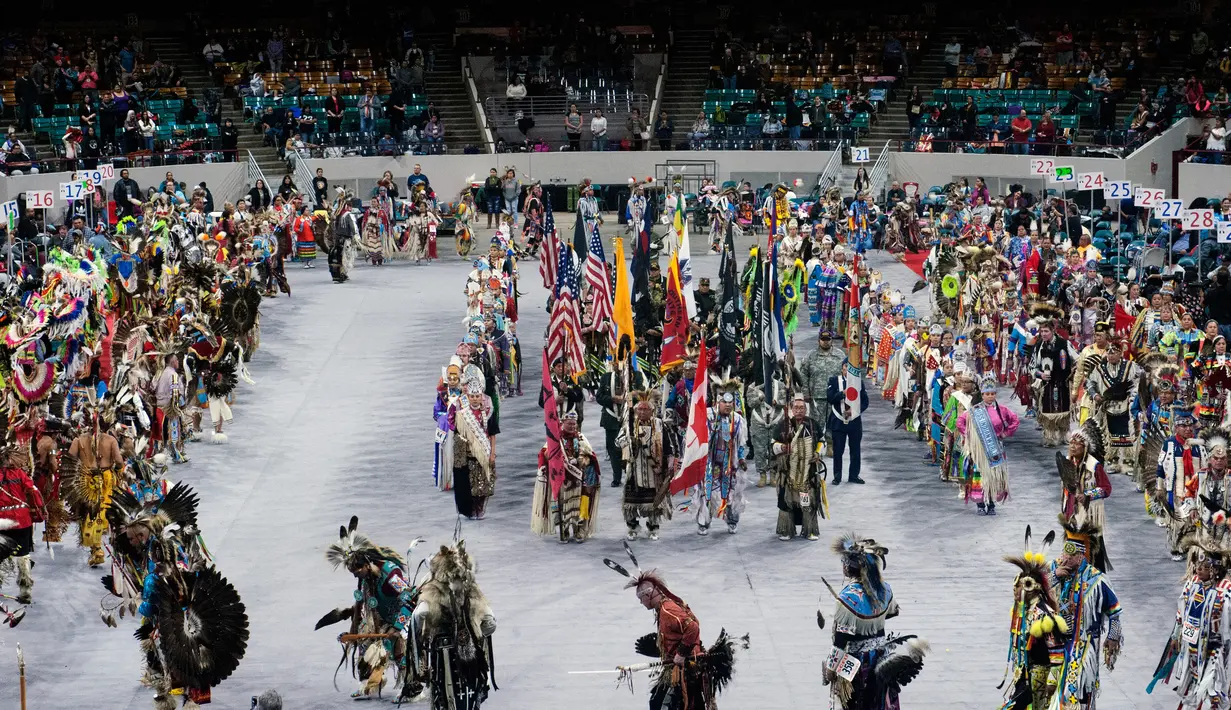 Para penari asli Amerika bersiap untuk berpartisipasi dalam Grand Entry of the Denver March Powwow di Denver, Colorado (24/3). Para penari mengenakan pakaian tradisional serta hiasan kepala, sepatu dan syal dari sukunya masing-masing. (AFP/Jason Connolly)