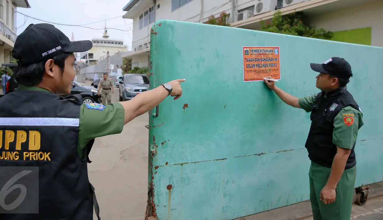 Petugas memasang plang di depan PT DKB Dok Perkapalan Galangan I, Tanjung Priok, Jakarta, Senin (23/11). Langkah ini diambil sebagai peringatan bagi para wajib pajak (WP) kelas menengah ke atas mencapai ratusan miliar. (Liputan6.com/Faizal Fanani)