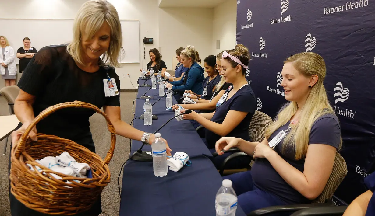 CEO Banner Desert Medical Center, Laura Robertson (kiri) membagikan pakaian bayi kepa 16 suster di bagian gawat darurat yang sedang hamil bersamaan selama konferensi pers di sebuah rumah sakit di Mesa, Arizona, 17 Agustus 2018. (AP/Ross D. Franklin)