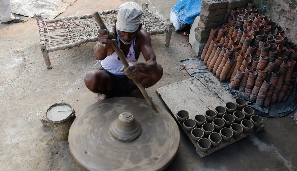 Pengrajin tembikar membuat lampu minyak yang terbuat dari tanah liat menjelang festival Diwali di Prayagraj, India, Kamis (17/10/2019).  Saat Diwali, seluruh kota akan dihiasi diya, lampu minyak tradisional yang terbuat dari tanah liat, lampion, dan lampu lainnya. (AP/Rajesh Kumar Singh)