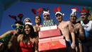 Para peserta mengenakan kostum bernuansa natal seperti topi Santa Klaus dan topi tanduk rusa saat mengikuti tradisi lomba renang unik saat natal di pelabuhan tua Barcelona (Port Vell Barcelona), Spanyol, Senin (25/12/2023) waktu setempat. Lomba tersebut dimenangkan oleh Edward Poeschke dengan mencatatkan waktu 3 menit 17 detik. (AFP/Josep Lago)