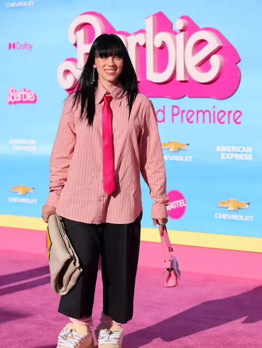 Billie Eilish tampil super menggemaskan di red carpet premiere Barbie. Sepatu yang besar, dipadu dengan oversized pants berwarna hitam, kemeja bergaris berwarna pink, dan dasi merah yang mengkilap. Foto: Instagram.