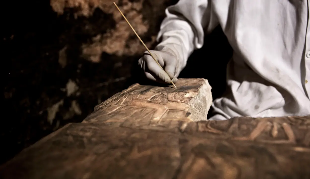 Arkeolog meneliti artefak yang ditemukan di dalam sebuah makam kuno dekat piramida terkenal Mesir di Saqqara, Giza, Sabtu (10/11). Puluhan mumi kucing dan koleksi langka mumi kumbang scarab telah ditemukan di tujuh sarkofagus. (AP/Nariman El-Mofty)