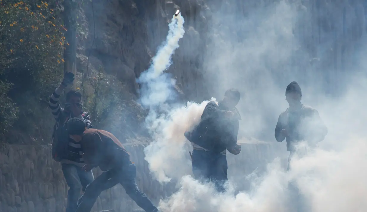 Demonstran melempar kembali gas air mata ke arah polisi di La Paz, Bolivia, Selasa (21/2). Demonstran protes kebijakan baru Presiden Evo Morales terkait petani daun koka. (AP Photo / Juan Karita)