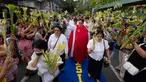 Seorang pemuka agama Katolik memberkati umat yang memegang daun palem di sepanjang jalan selama prosesi untuk menandai Minggu Palma sebagai bagian dari devosi jelang perayaan Paskah di Manila, Filipina pada 13 April 2025. (Ted ALJIBE/AFP)