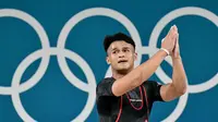 Rizki Juniansyah berhasil mencatat total angkatan 354 kg usai sukses mengangkat beban 155 kg snatch dan 199 kg clean and jerk. (Miguel MEDINA/AFP)