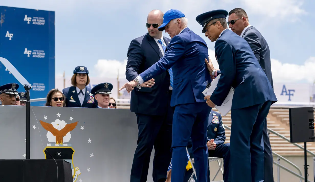 Setelah terjatuh, Biden tampak menunjuk ke arah karung pasir di dekatnya dan berpegangan pada anak tangga, yang menunjukkan bahwa dia tersandung. (AP Photo/Andrew Harnik)