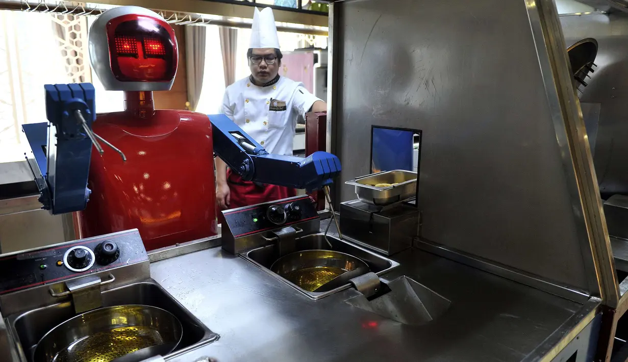 Seorang koki memperhatikan robot yang sedang membuat masakan di restoran robot di Hefei, China, Jumat (26/12/2014). (REUTERS/Stringer)