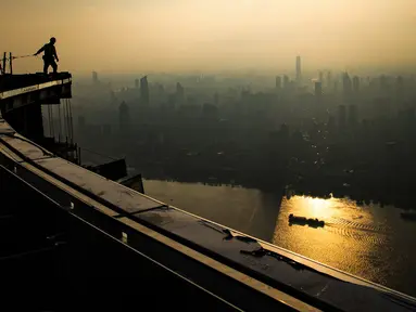 Seorang pekerja konstruksi bekerja di ketinggian sekitar 500 meter di lokasi pembangunan sebuah bangunan bertingkat tinggi di Wuhan, Provinsi Hubei, China tengah (11/8/2020). Para pekerja konstruksi harus menghadapi ketinggian dan panasnya udara musim panas. (Xinhua/Xiao Yijiu)