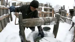 Mikhail Baburin (66) mengambil air dari sumur rumahnya di desa Mikhailovka di Siberia, 5 Desember 2016. Baburin adalah mantan anggota angkatan laut, pekerja Tongkang, dan karyawan pabrik peralatan militer di Krasnoyarsk. (REUTERS/Ilya Naymushin)