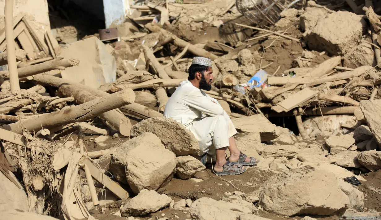 Seorang pria duduk di dekat rumahnya yang rusak setelah banjir besar di provinsi Maidan Wardak di Afghanistan tengah, Minggu, 23 Juli 2023. (AP Photo)