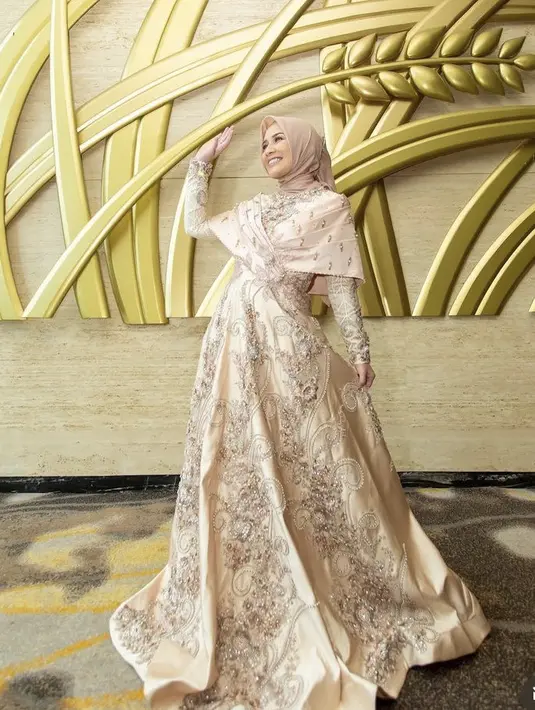 Ia pun tampil mewah dengan dress berpayet rok mengembangnya, dipadukan hijab warna cokelat yang serasi dengan dressnya. Credit: Instagram @dine.pearl