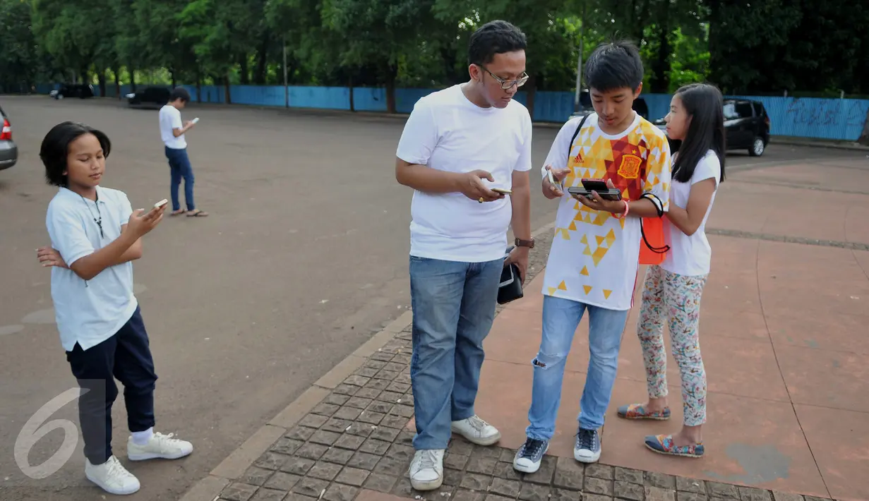 Sejumlah pemuda dan anak- anak saat berburu pokemon di Kawasan Senayan, Jumat (15/7).Permainan Pokemon Go ini menugaskan para pemainnya untuk memburu pokemon mereka sendiri. (Liputan6.com/Gempur M Surya)