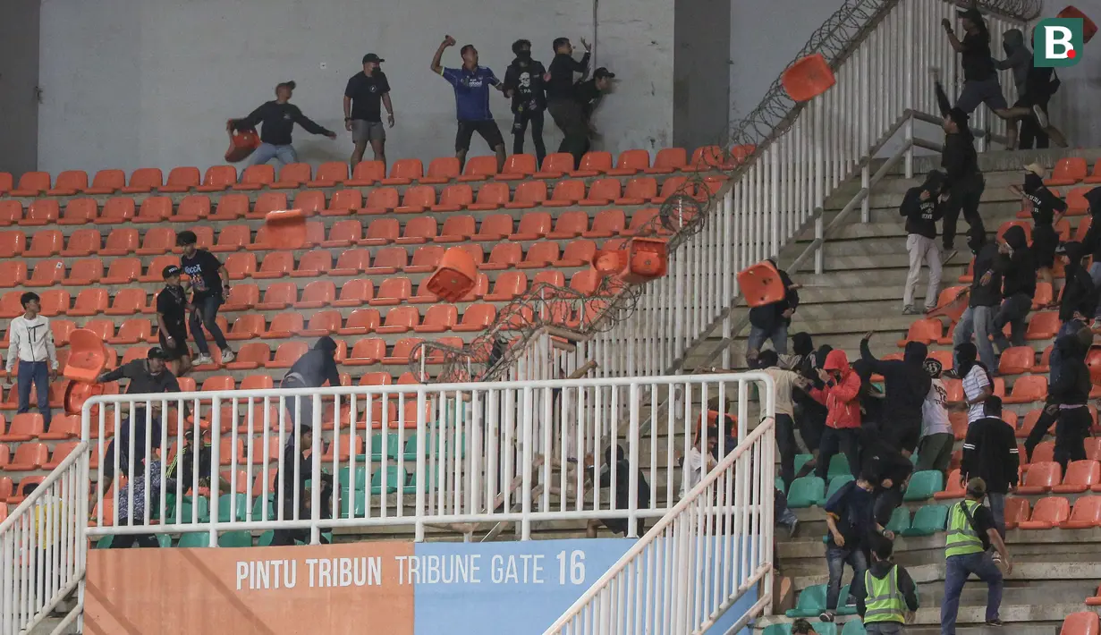 Terlihat dua kelompok suporter Persib Bandung dan Persis Solo saling serang di antara tribune kosong yang jadi sekat keduanya. Kursi stadion terlihat beterbangan dan jadi objek penyerangan kedua kelompok suporter. (Bola.com/Bagaskara Lazuardi)