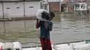 Pekerja mengangkut barang menggunakan perahu menuju dermaga di Desa Pantai Mekar, Muaragembong, Kabupaten Bekasi, Senin (6/12/2021). Jasa angkut barang menggunakan perahu tersebut banyak diminati warga untuk mempersingkat waktu perjalanan. (Liputan6.com/Herman Zakharia)