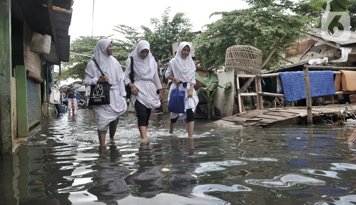 Sejumlah anak sekolah melintasi banjir yang masih merendam Kampung Rawa Indah, Jakarta Utara, Senin (24/2/2020). Kampung yang terletak di dua kelurahan, yakni Sukapura dan Pegangsaan Dua tersebut masih terendam banjir hingga sore ini dengan ketinggian air 30-50 cm. (merdeka.com/Iqbal S Nugroho)