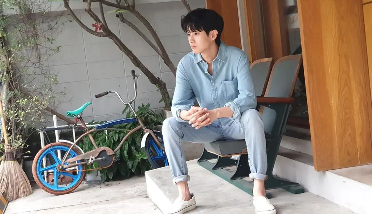 Memadukan kemeja serta celana berbahan jeans, gaya santai Woo Shik ini tak lepas dari perhatian netizen. Ia pun memilih menggulung kemeja serta celananya di bagian lengan serta memadukan dengan sneakers putih. (Liputan6.com/IG/@dntlrdl)