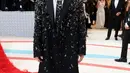 Cai Xu Kun tampil stunning dengan mantel sampai dasi dengan detail bling bling dari Prada. Lengkap dengan aksesori kipas bertulisan Tiongkok dalam genggaman penyanyi dan rapper asal China ini. [@themetgalaofficial]