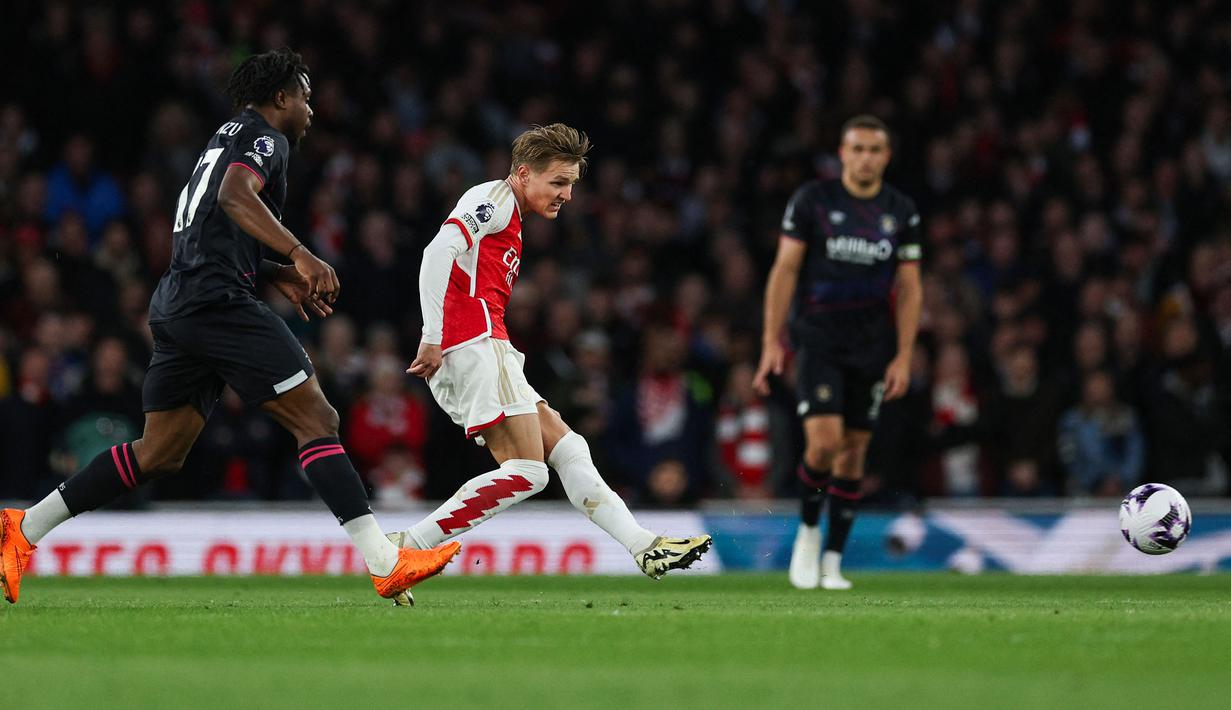 Gelandang sekaligus kapten tim Arsenal, Martin Odegaard melepaskan tendangan yang menghasilkan gol pertama timnya ke gawang Luton Town pada laga pekan ke-31 Premier League 2023/2024 di Emirates Stadium, London, Rabu (3/4/2024) malam. (AFP/Adrian Dennis)