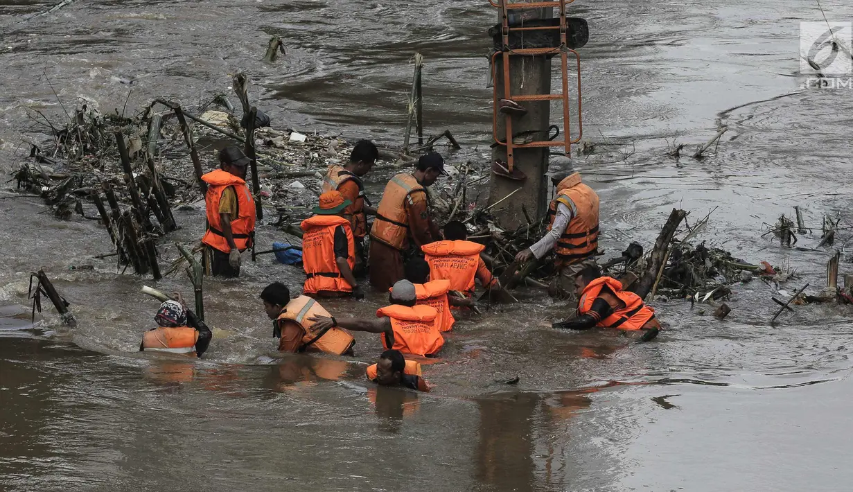 Sejumlah pasukan oranye berjibaku membersihkan sampah batang kayu dan bambu yang tersangkut di aliran sungai Ciliwung di kawasan Sudirman, Jakarta, Jumat (9/2). (Liputan6.com/Faizal Fanani)