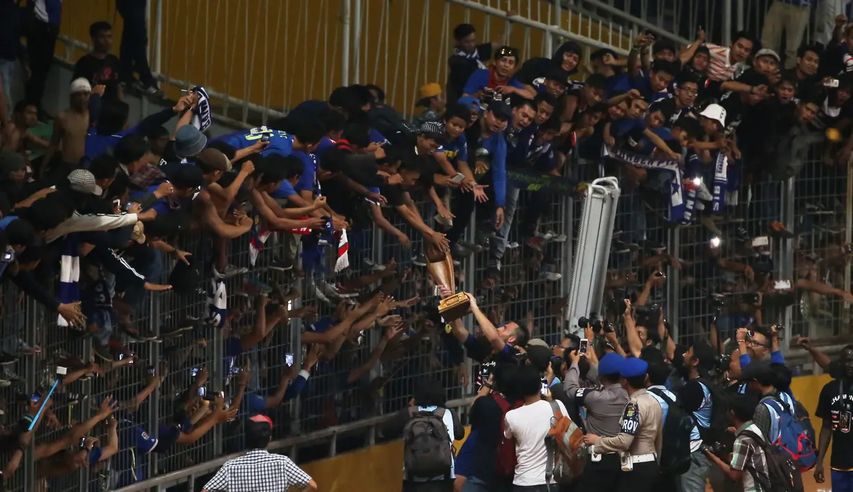 Suporter berebutan memegang trofi juara usai Final Piala Presiden 2015 di Stadion Gelora Bung Karno, Jakarta,Minggu (18/10/2015). (Bola.com/Nicklas Hanoatubun)